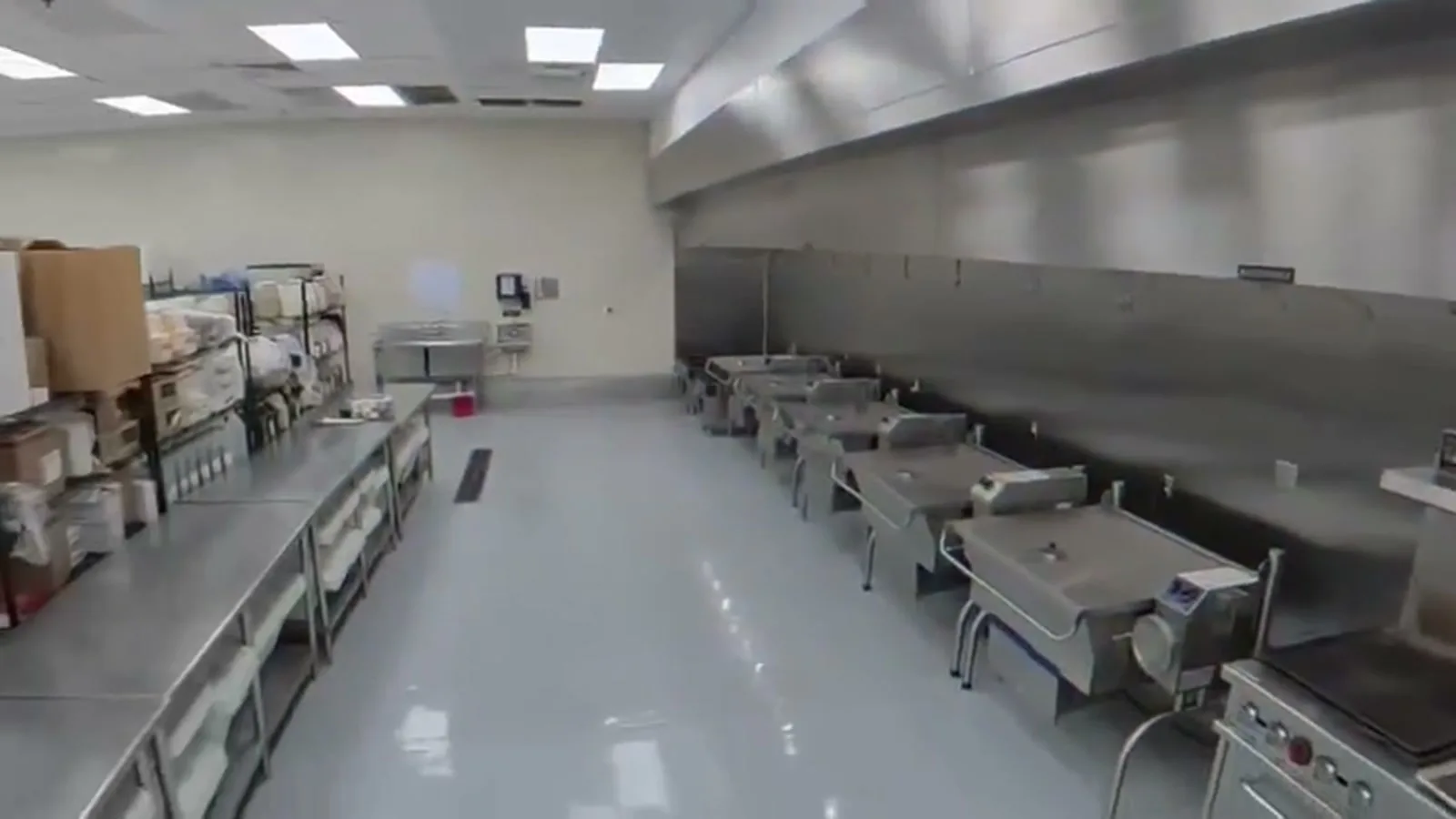 A seamless light floor in a commercial kitchen lined with stainless equipment